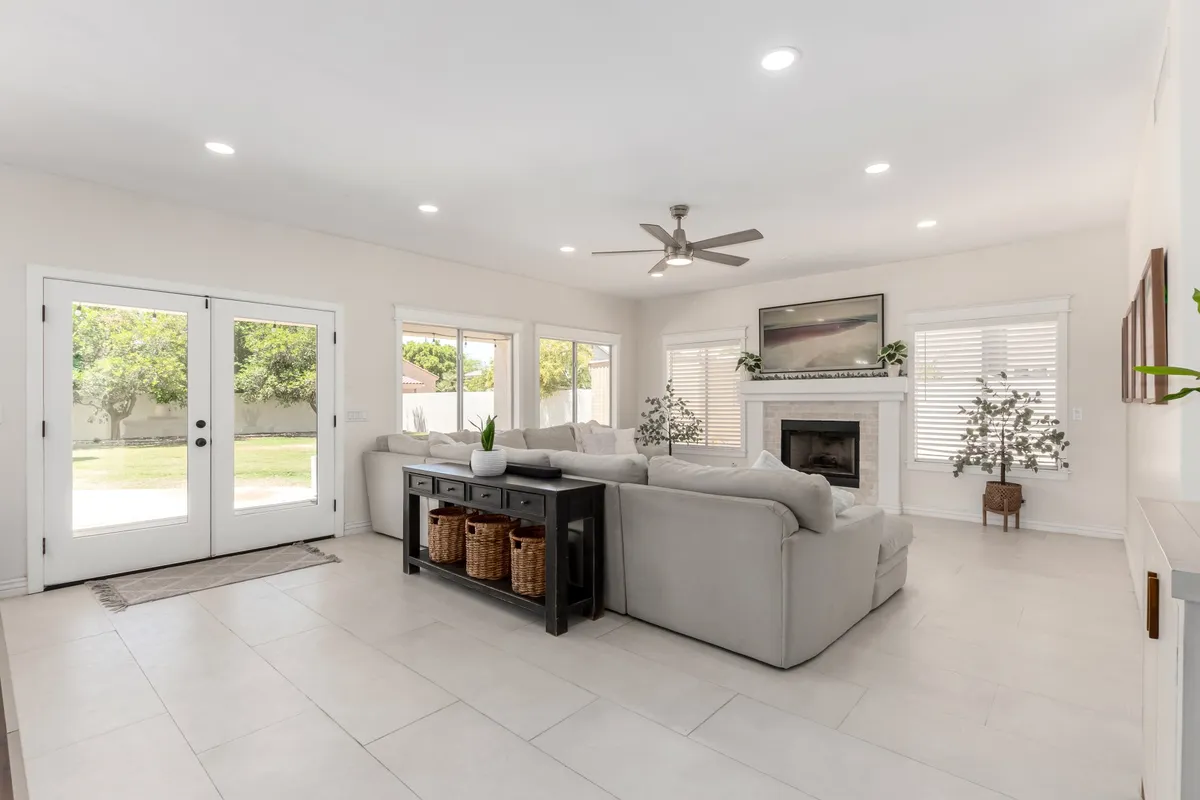 This image showcases a cozy living area with a large sectional sofa, a fireplace as a gathering focal point, and double doors that open to the outdoor area. The layout encourages relaxation and togetherness, with natural light inviting guests to flow easily between indoor comforts and the outdoor setting.