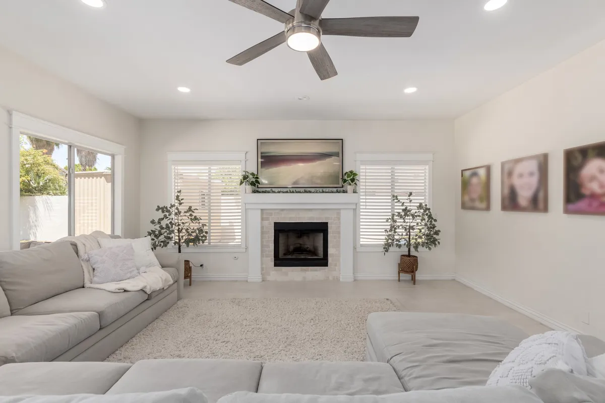 This image features a large sectional sofa arranged around a cozy fireplace, with artwork on the walls adding a personal touch. The space looks ideal for socializing, relaxing with family, or hosting guests, and the inviting atmosphere is enhanced by the warm, soft lighting.
