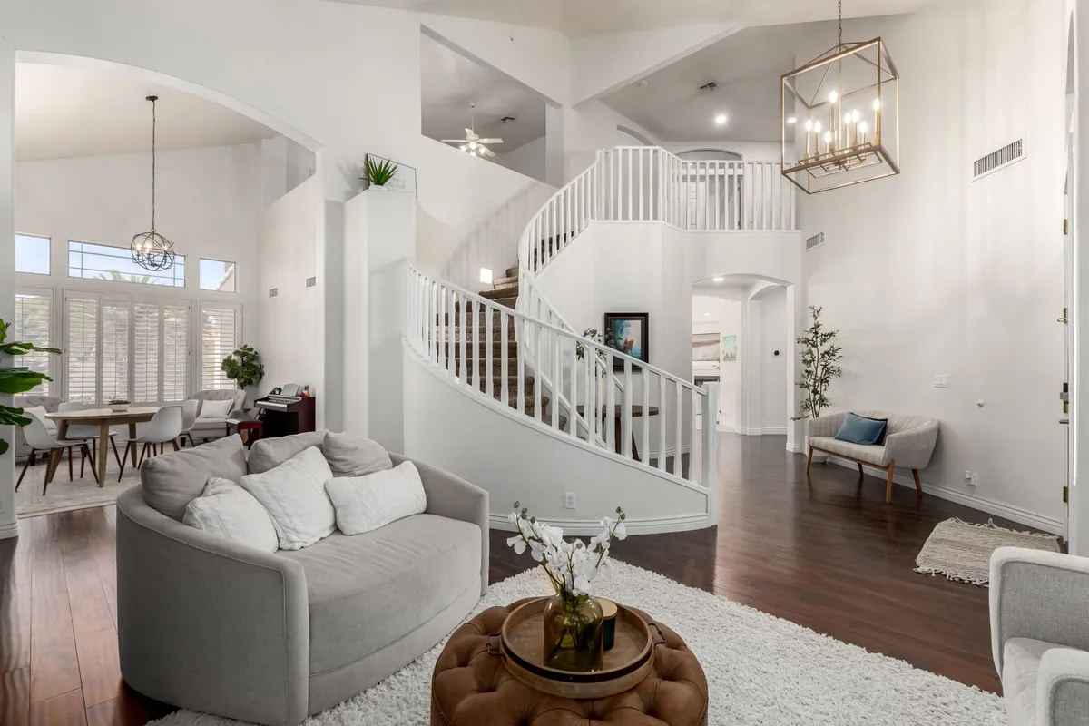 A beautifully lit interior showing a spiral staircase, comfortable seating area, and adjacent dining space under a striking chandelier. The open layout visually links the living and dining zones, reinforcing the idea of seamless flow and shared experiences.