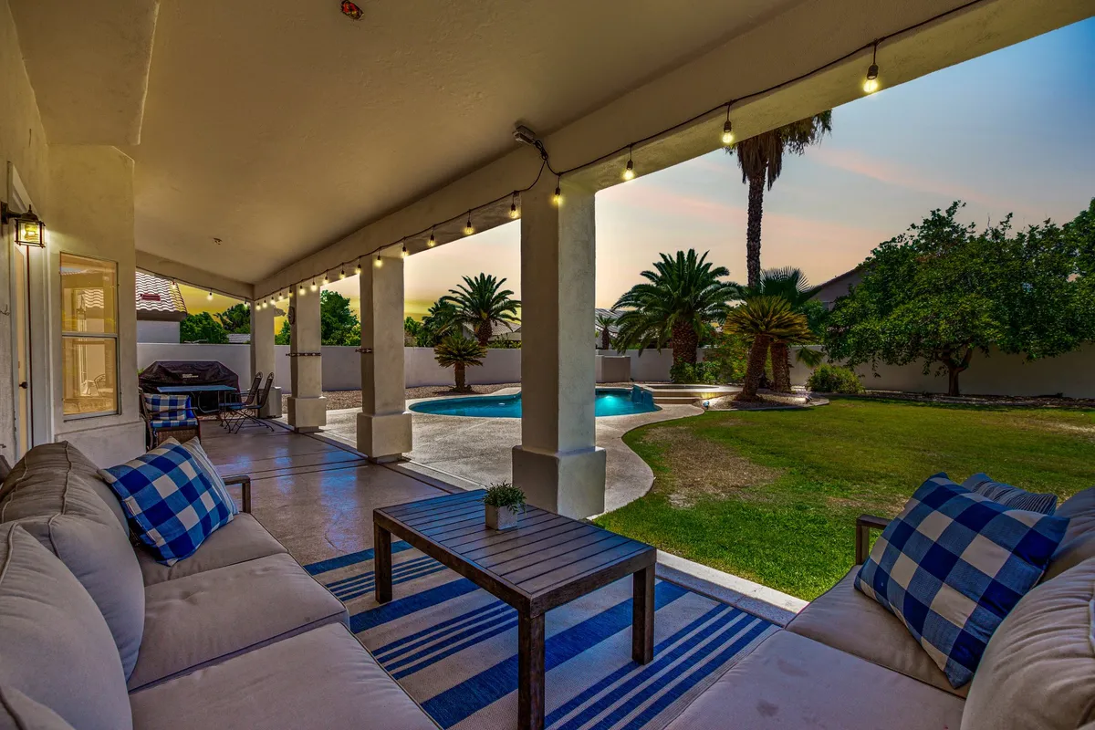 A well-appointed backyard featuring an inviting swimming pool, comfortable outdoor seating area, lush palm trees, and a manicured garden. The space is clearly designed for both relaxation and entertaining, with cozy spots for stargazing, dining, or socializing outdoors.