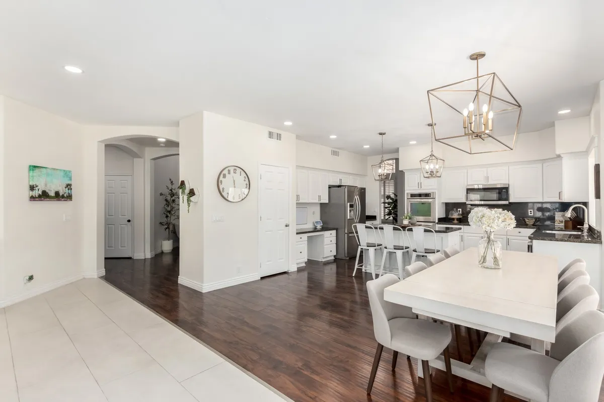 A contemporary dining space anchors this image, featuring a large dining table, a kitchen island, and stylish lighting fixtures. The view captures a warm, welcoming ambiance that invites group meals, celebrations, and memorable moments. Decorative wall art adds character to the open floor plan.