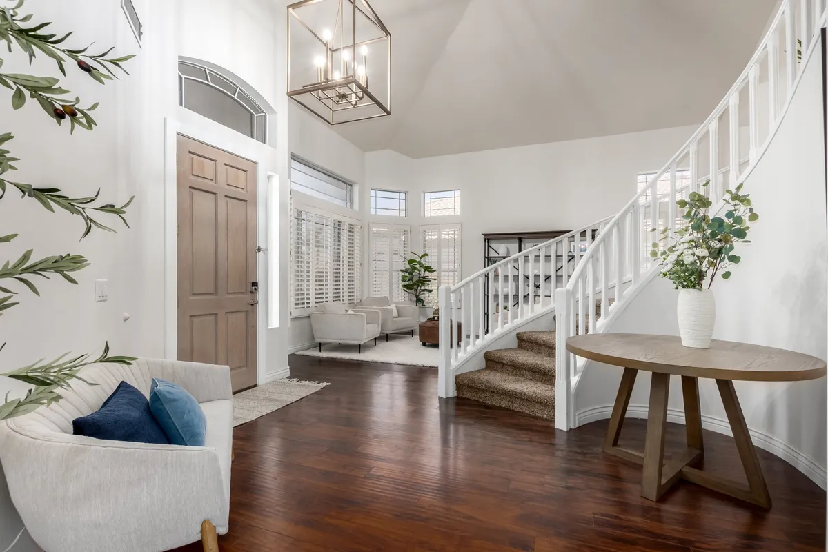This entryway image shows a staircase, front door, seating area, lighting fixture, and decorative plants, providing a glimpse of the warm, welcoming entrance to the home. The open space hints at easy transitions from the outside world to the comfort of the interior.