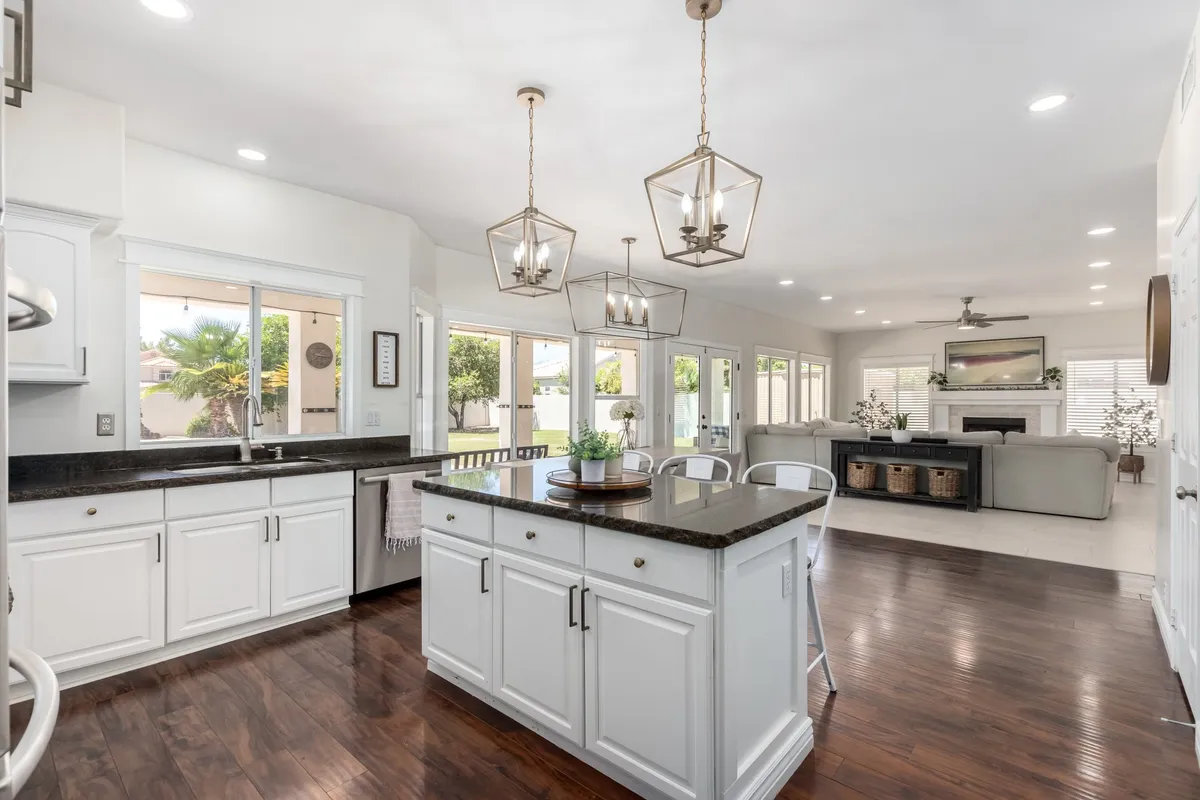 An inviting kitchen highlighted by a central island countertop, stylish hanging lights, and an open floor plan that flows seamlessly into adjoining spaces. The setting promotes easy conversation and togetherness, reflecting the kitchen as a hub for family and friends.
